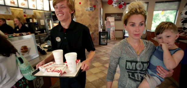 mom and son at chick fil a. Chick Fil A employee serves meal